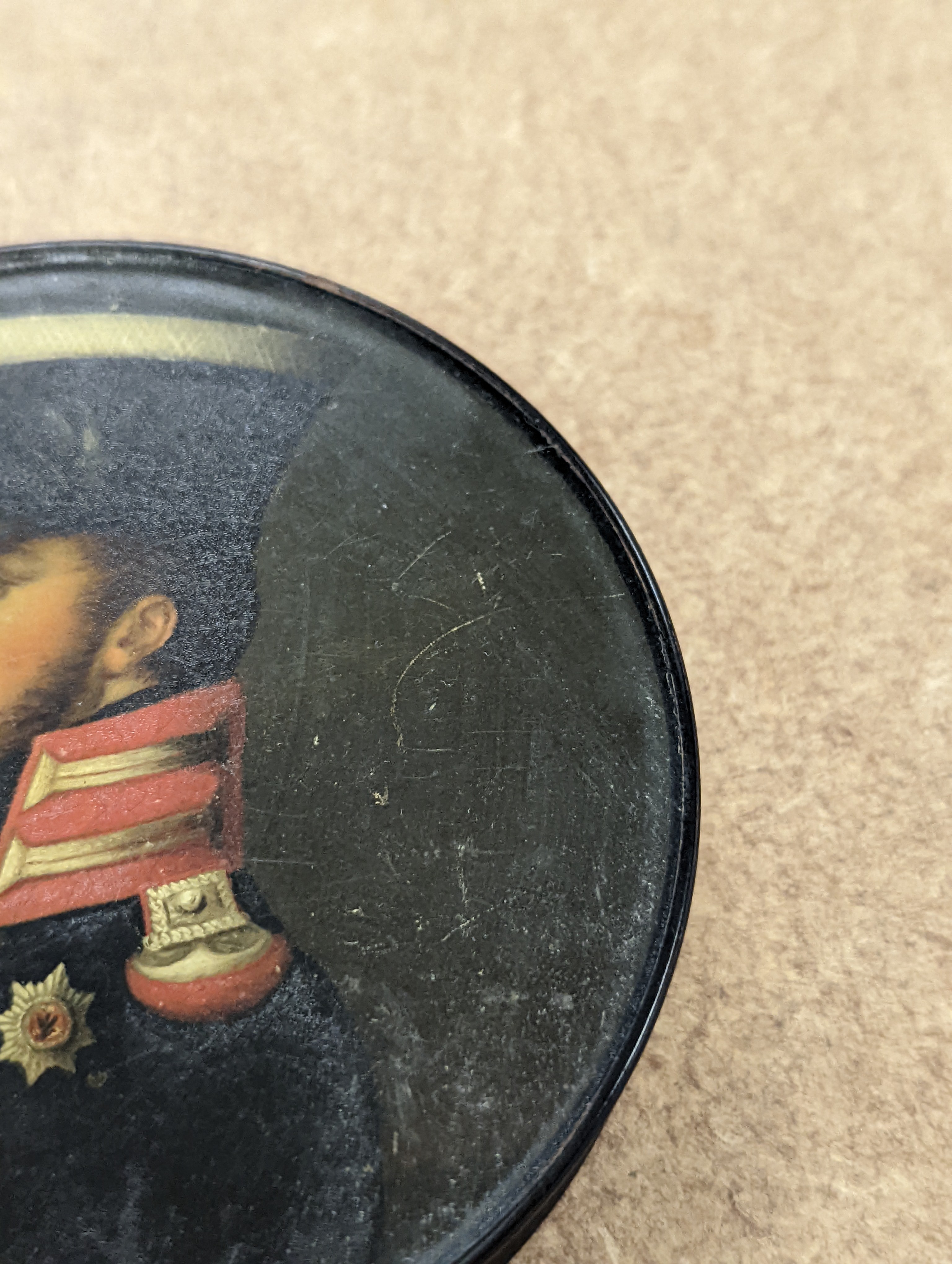 A 19th century Stobwasser papier mache ‘Henriette Sonntag’ portrait snuff box, c.1830, 9.7cm diameter and a 19th-century papier mache snuff box painted with a portrait of a German hussar, 9.4cm (2)